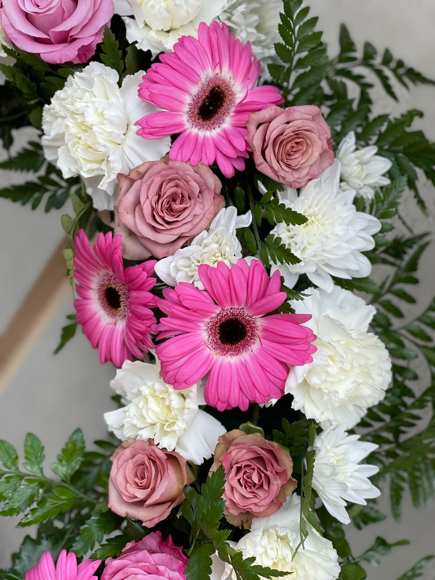 Detaliu coroană funerară pastelată cu trandafiri mov și gerbera roz - aranjament elegant - coroane funerare Reșița