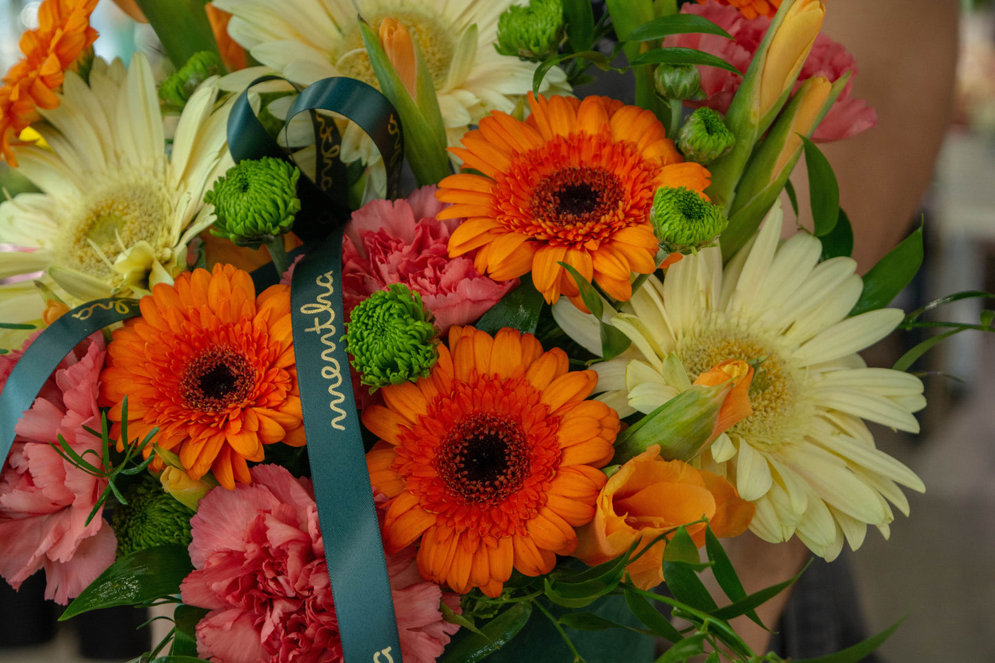 Detaliu din cutia rafinată cu gerbera și garoafe în nuanțe de roz, portocaliu și galben pastel.