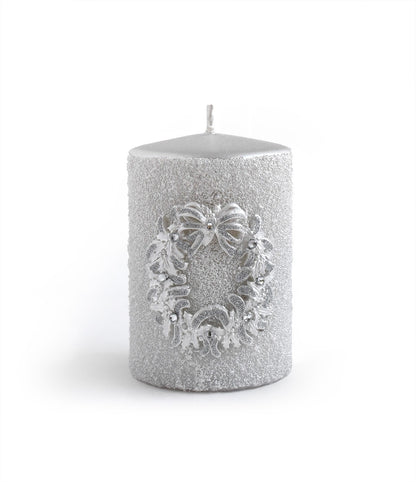Adaugă un strop de eleganță rafinată în decorul tău de Crăciun cu această lumânare argintie, înconjurată de o cunună decorativă în aceeași nuanță metalică. Combinația de texturi și lucii creează o atmosferă caldă și sofisticată, perfectă pentru masa de sărbători, un șemineu sau ca element central într-un aranjament festiv. Detaliile fine ale cununii argintii reflectă lumina lumânării, oferind un joc vizual discret și șic.