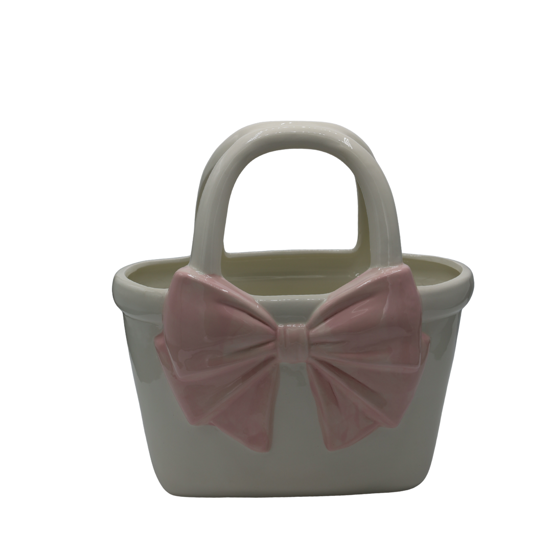 Vază decorativă realizată din ceramică în formă de poșetă elegantă, cu finisaj alb și accente roz tip fontă, ideală pentru decoruri moderne și feminine. Aspectul sofisticat și designul inspirat din accesorii fashion transformă această piesă într-un element decorativ spectaculos pentru living, dormitor, birou sau dressing. Este perfectă pentru flori decorative și reprezintă o alegere excelentă pentru cadouri elegante oferite la aniversări, casă nouă sau evenimente speciale.