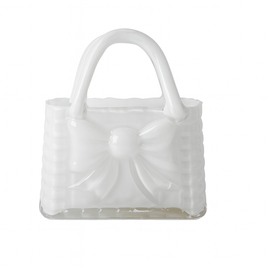 Vază decorativă din sticlă albă în formă de poșetă, concepută pentru interioare luminoase și elegante. Designul său curat adaugă rafinament și simplitate, fiind ideală pentru decor minimalist sau modern. Se potrivește perfect cu flori delicate și este o alegere excelentă pentru cadouri de casă nouă sau decoruri premium.