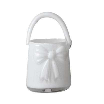 Vază decorativă din sticlă albă în formă de poșetă, concepută pentru interioare luminoase și elegante. Designul său curat adaugă rafinament și simplitate, fiind ideală pentru decor minimalist sau modern. Se potrivește perfect cu flori delicate și este o alegere excelentă pentru cadouri de casă nouă sau decoruri premium.