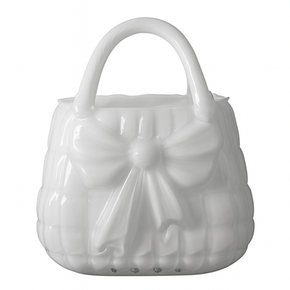 Vază decorativă din sticlă albă în formă de poșetă, concepută pentru interioare luminoase și elegante. Designul său curat adaugă rafinament și simplitate, fiind ideală pentru decor minimalist sau modern. Se potrivește perfect cu flori delicate și este o alegere excelentă pentru cadouri de casă nouă sau decoruri premium.