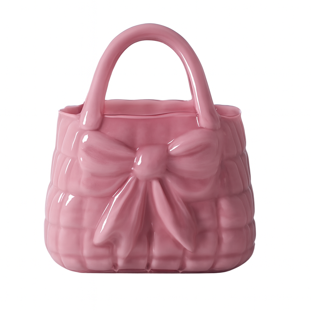Vază decorativă din sticlă în formă de poșetă roz, piesă feminină și elegantă care adaugă un accent delicat și romantic în orice interior. Este ideală pentru flori proaspete sau artificiale și se potrivește perfect în dormitor, living sau spații creative. Este și o alegere inspirată de cadou pentru ocazii speciale sau decoruri moderne.