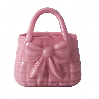 Vază decorativă din sticlă în formă de poșetă roz, piesă feminină și elegantă care adaugă un accent delicat și romantic în orice interior. Este ideală pentru flori proaspete sau artificiale și se potrivește perfect în dormitor, living sau spații creative. Este și o alegere inspirată de cadou pentru ocazii speciale sau decoruri moderne.
