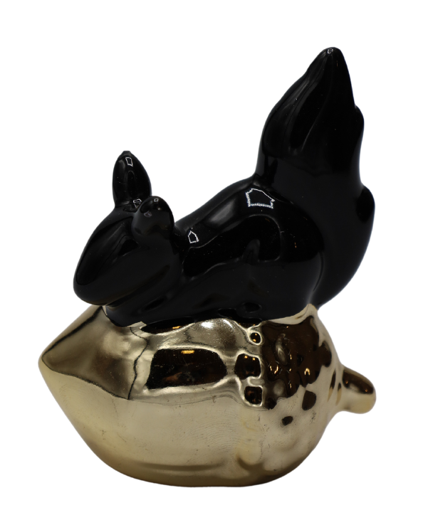 Mini figurină decorativă veveriță pe ghindă cu finisaj negru și detalii aurii sofisticate, creată pentru decoruri moderne și elegante. Contrastul dintre negru și auriu oferă un aspect premium și contemporan care completează perfect livingurile glam, birourile moderne sau rafturile decorative rafinate. Simbol al prosperității și energiei pozitive, această piesă decorativă este ideală pentru cadouri de casă nouă, aniversări sau pentru persoane pasionate de design interior modern și accesorii decorative